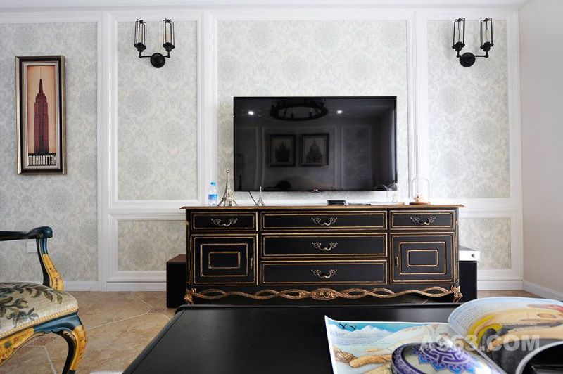 电视背景墙在颜色的选择上十分素净，黑色镶金电视柜给人一种华丽之感。古典壁灯的设计，充满韵味。
