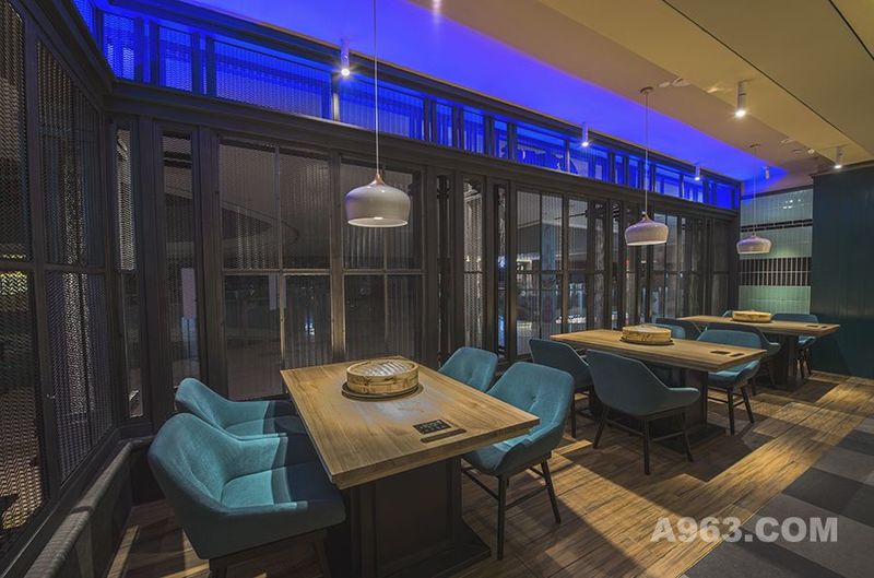 用餐区采用两种不同明度的蓝色，搭配棕黄色的原木餐桌，并用象牙白色的吊灯加以点缀，轻松而又惬意。
