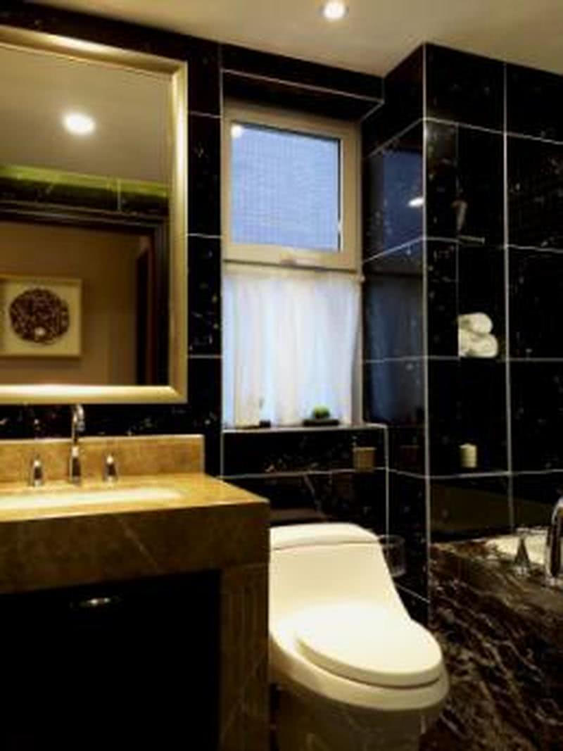 卫生间的设计以黑色大理石作为背景墙，配合深邃的碎纹米黄色洗手台，显得整个屋子简洁大方，自然沉稳。
