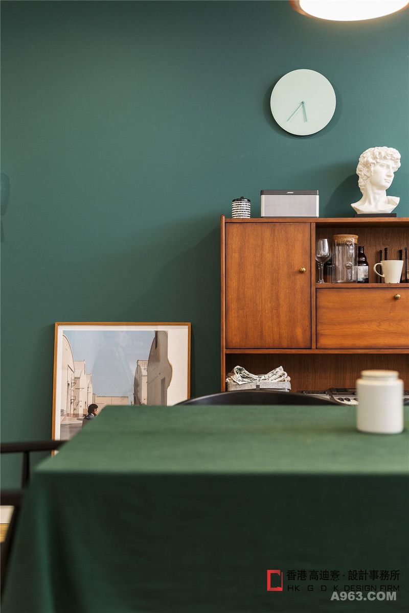 蓝绿色圆形小挂钟跟墨绿色的背景墙形成绝佳视觉体验，同属于绿色系，色度的递进即不会减弱背景的存在感，也突出了挂钟的点睛存在，大卫石膏增加一份复古文艺气息。