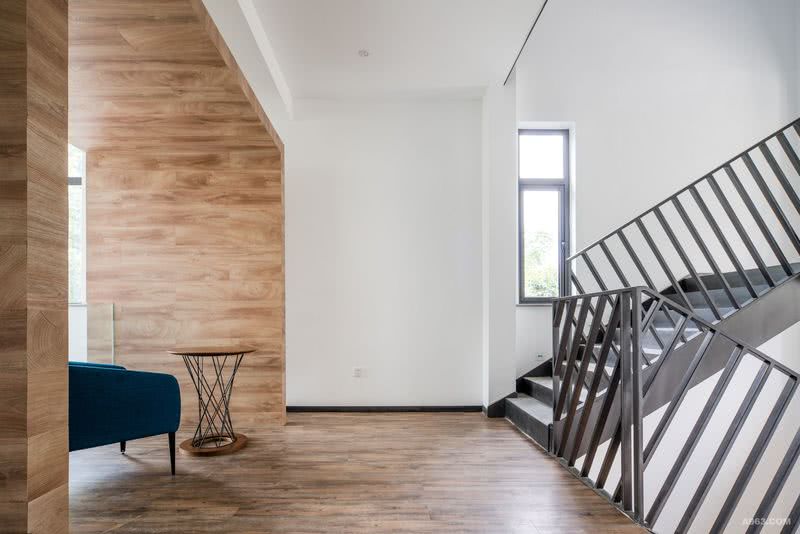 设计师利用了水泥木纹的凹凸纹路和低调的色泽，表现出装修色系的沉稳，外加大面积的原木墙面，空间的自然气息瞬间提升。楼梯的镂空设计，让空间更加通透，避免增添空间负担的可能性。