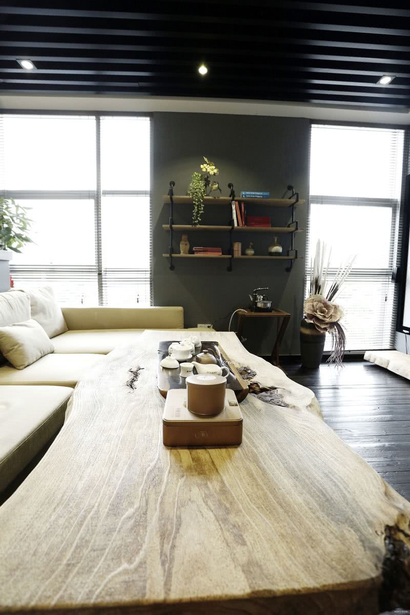 米色的沙发和原木色的茶几相呼应，浅色的家具和重色的天花地板色彩对比强烈，形成视觉中心。