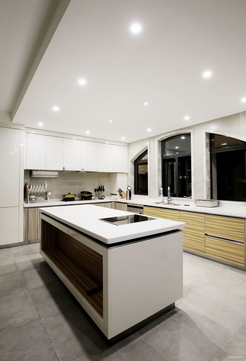 厨房的空间足够大，设置了一个中岛台，白色的橱柜仿佛为其量身定做，顶天立地的设计不仅增加收纳空间也令空间看上去更加美观完整。厨房的窗框造型耐看有趣，是厨房的亮点之一。