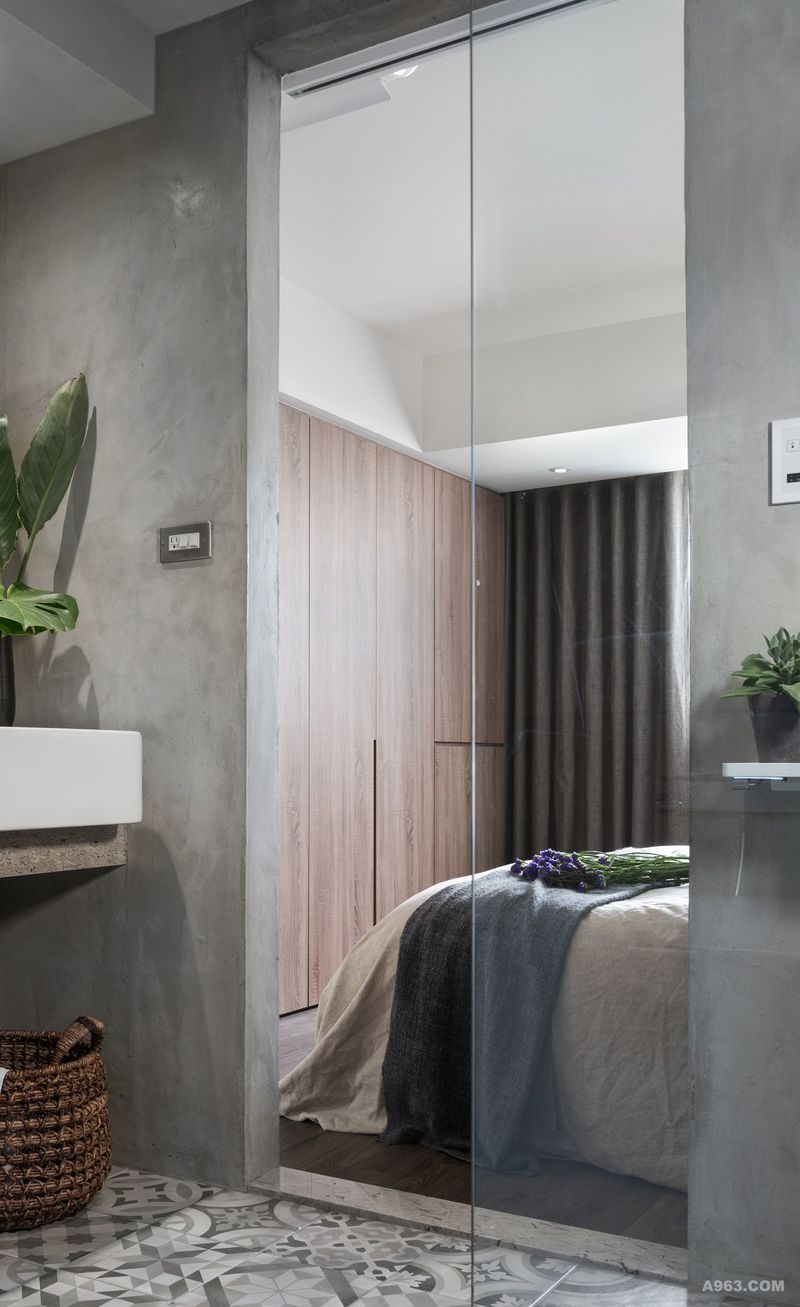 浴室以鋁框灰色玻璃拉門成為主臥室空間的延伸區域，延續主臥室自然色調，牆面為質感低調的水泥粉光牆，部分拼貼復古灰色花磚，營造優雅工業風的浴室。