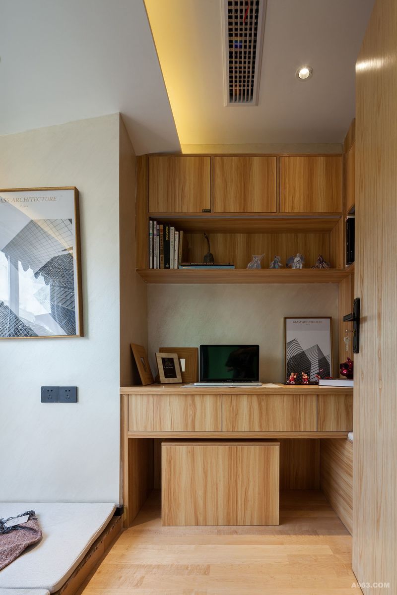 纯木色写字台被合理分割，放置各种手办，细心的设计师还在写字台的一侧安置木条凳，使书房兼具会客功能。