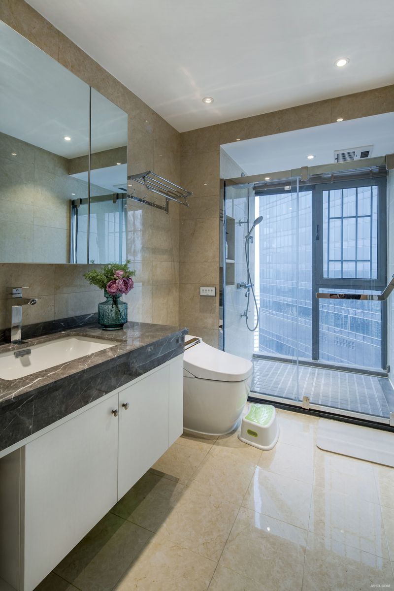 米色的浴室简洁大气，木饰面的洗漱台柜结合狭长的镜面将现代都市的摩登气质。