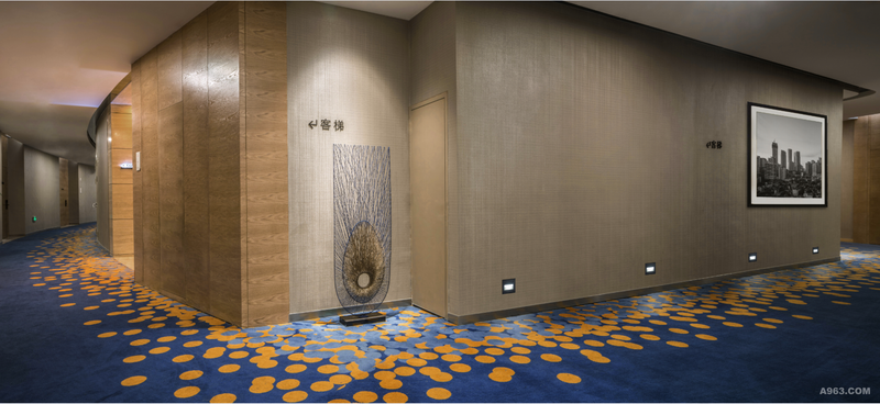 走道空间采用弧形设计，具有很强的延申感。橡木本色及宇宙蓝地毯构成主要基调，配上不规则点状图案来构筑空间静谧的内涵。