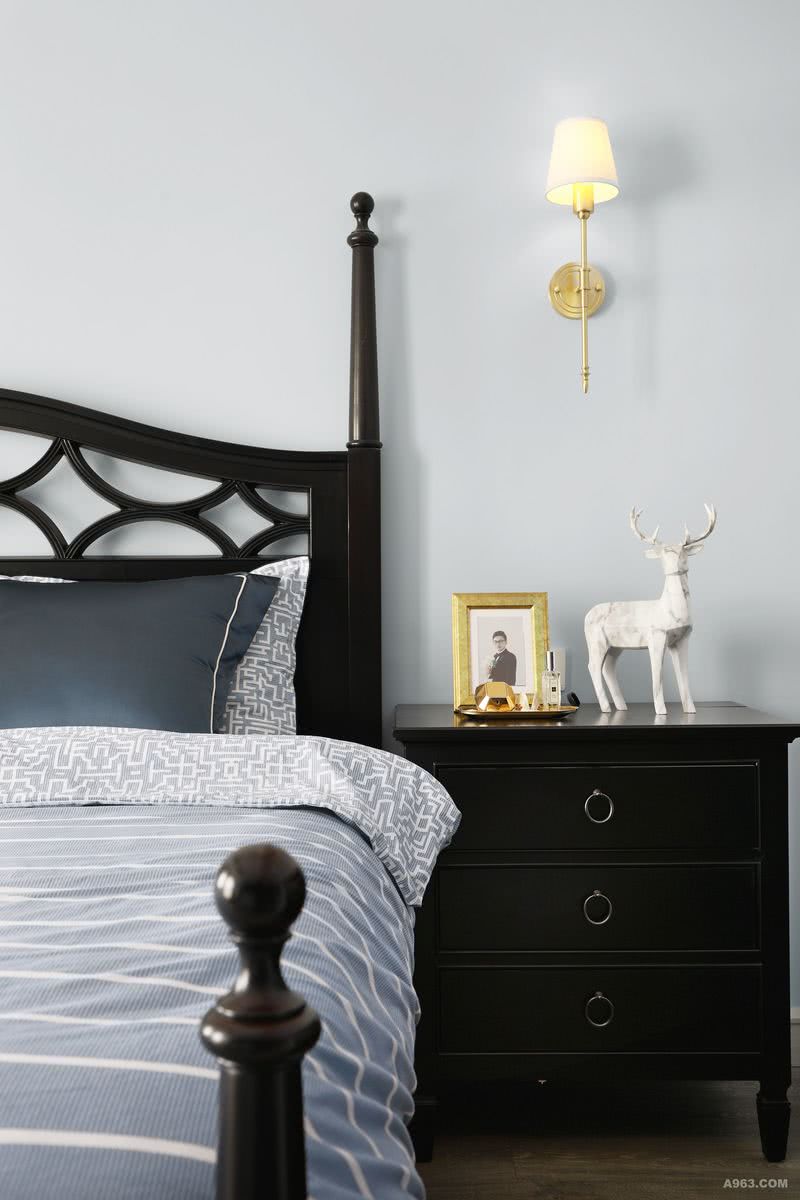 ▲卧室一角，便可纵观全局。黑色与蓝色双面的床品、浅蓝色的背景墙、金色的壁灯、个性抽象的动物装饰，以柔和的色彩结合深色的木质质感，刚柔并存的居住空间。