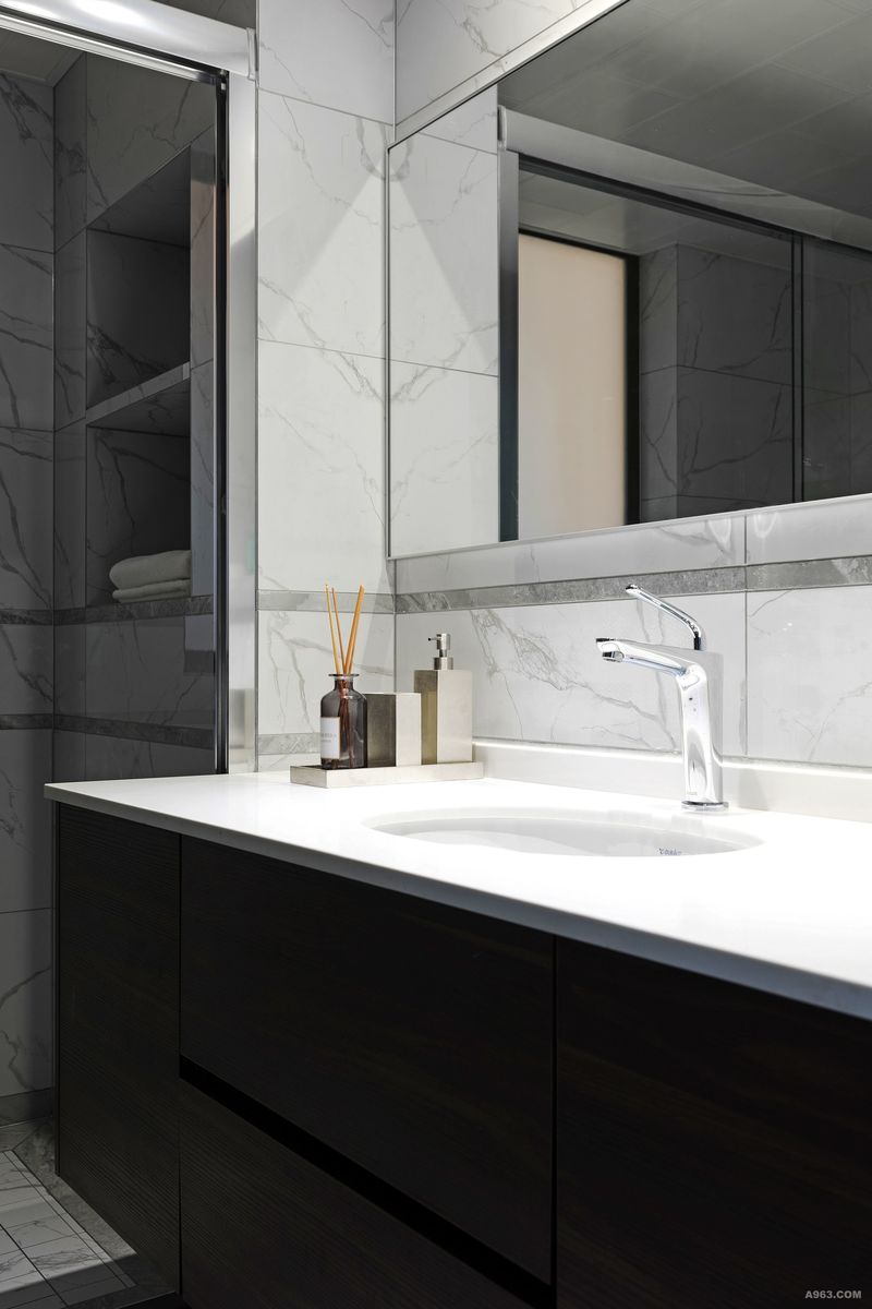 在卫生间的设计上，设计师追求实用性，遵循上轻下重循序渐进的原则，用简单大理石墙砖搭配白色台面，以黑色柜子作为颜色沉淀，使得空间更加稳重简洁。