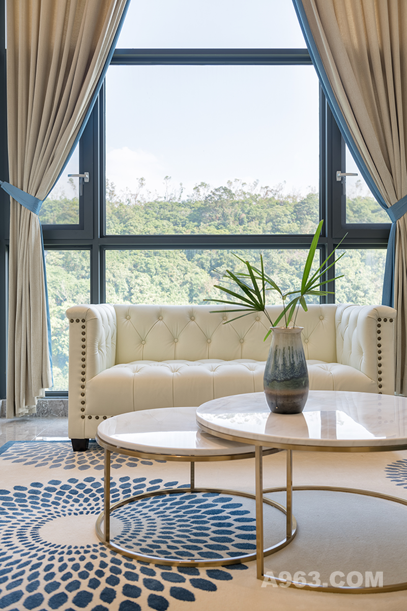 窗外的美景怎可错过呢？透过大大的落地窗，窗外的美景一览无遗，米色的皮质沙发透出了房间的一丝小奢华，再配以蓝色圆形点状地毯，一切仿佛刚刚好。