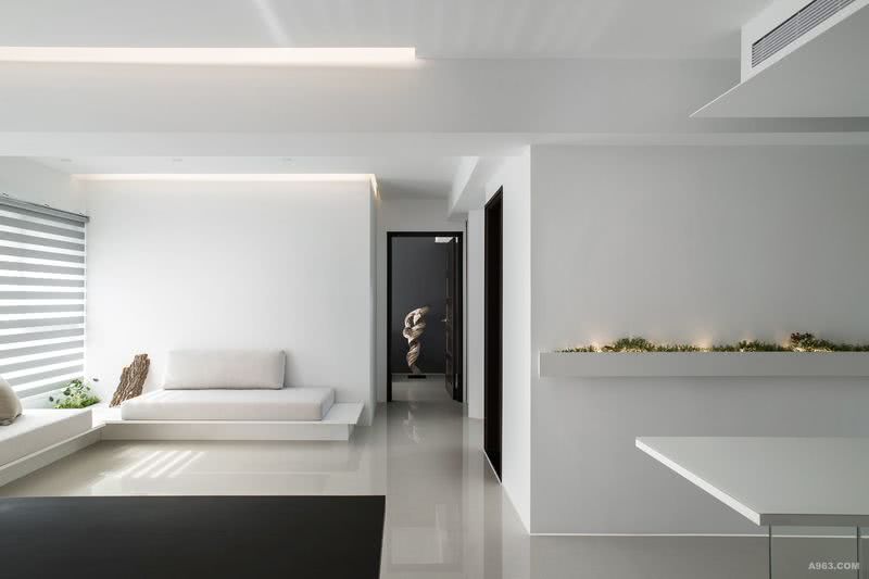 簡約客廳，白色系木作體、白烤玻面材和米色布料沙發座墊構成素淺基色背景。