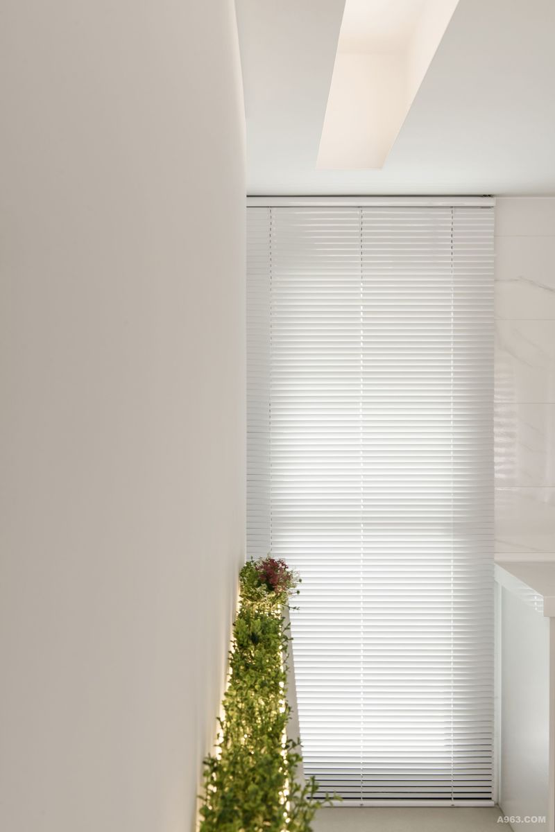 從高採光落地門窗進入的陽光，於白色透光薄片百葉的背影，把天花板光溝幾何和視覺腰帶連結。