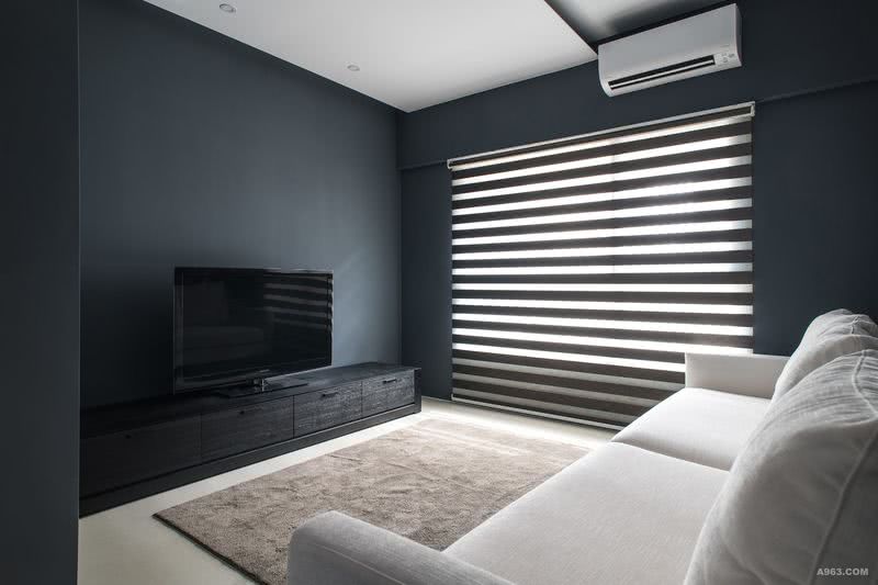 深色系的視聽室配置黑色的實木貼皮電視櫃和高背扶手之白沙發，呈現另一種設計風格－典雅沉穩。