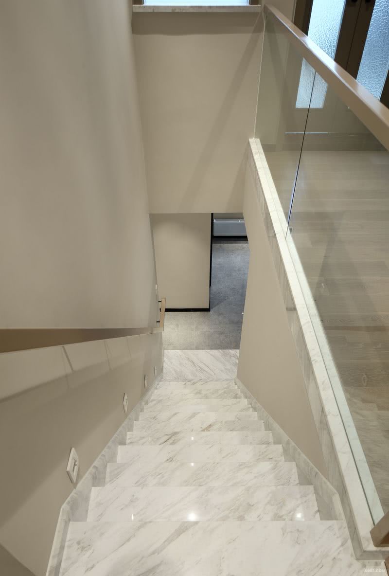 进过二楼楼梯便是进入二层，简单扶手作为墙面的点缀也作为功能性使用，感应地脚灯的设计让居住者在夜晚行走时得到便利性。大片玻璃栏杆的设计让空间视线尺度变大。
