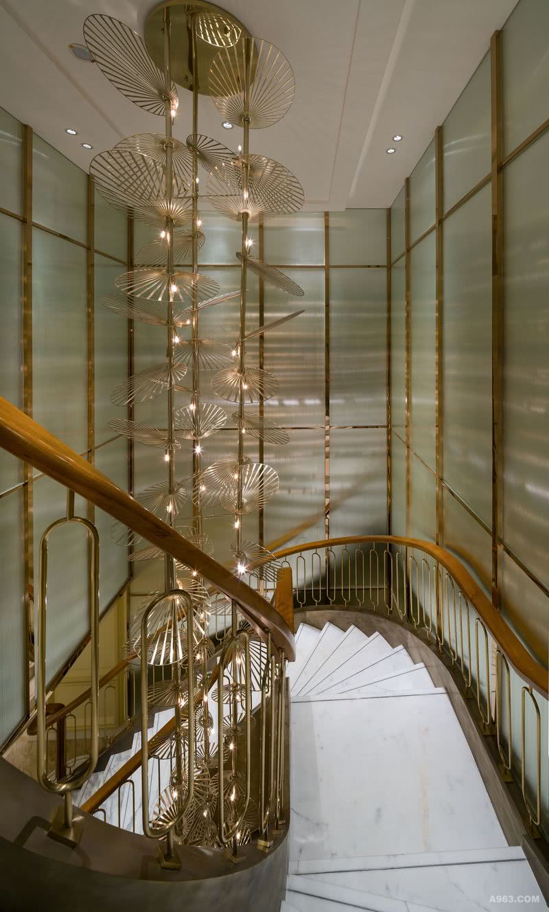 接驳三层和四层的楼梯：从公寓接待大堂到楼上的公共空间，既可以通过客房电梯到达，也可以从大堂尽头的扶手楼梯慢慢拾级而上，令住客如同在自己家里自由穿梭于各个场所一样。蜿蜒的楼梯设置木质扶手和亮铜色栏杆，环绕着贯通二层的金属悬挂雕塑，在周边金属饰条的哑光玻璃墙面映衬下，璀璨华丽又不失优雅沉稳。