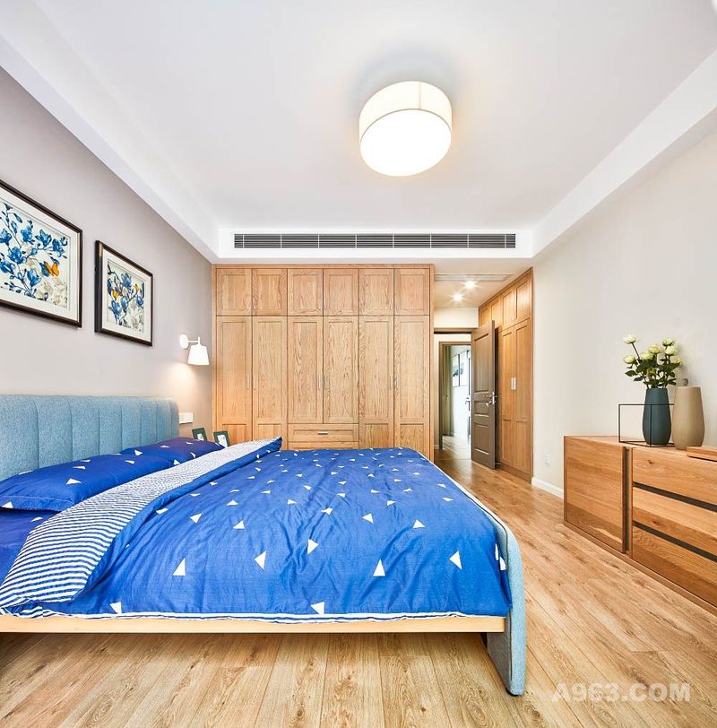 床头上挂着设计师与业主精心挑选的画作，蓝色的花儿与床相对应，整个空间散发出舒适宁静的就寝氛围。