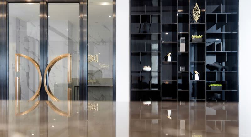 五楼办公室入口大门立面：大门拉手以LOGO的形式呈现加深公司专业形象，旁边艺术与功能专业融合的装饰柜灵动高级