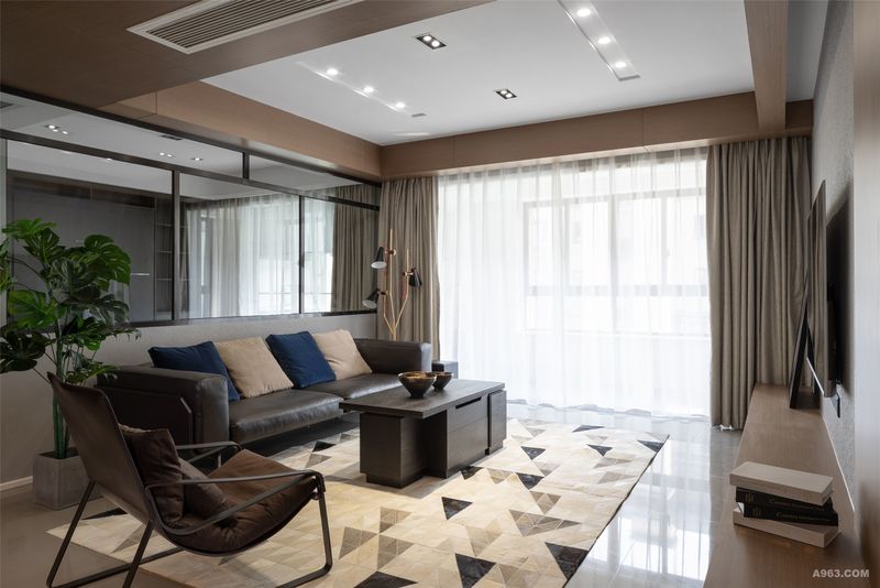 客厅选用灰色大理石地砖与黑色沙发搭配拉伸空间层次感，柔和的木质色调吊顶及电视造型墙柔化了空间厚重的气氛。