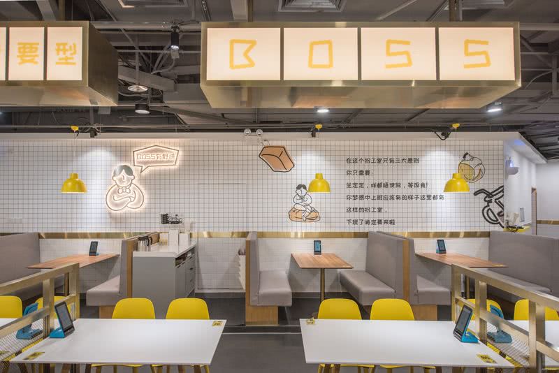 办公室上方运用配合空间主色调黄色的灯箱展示品牌主题“boss”，与灯具、桌椅以及墙绘形成统一。