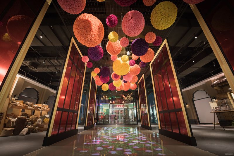 走进美食街的入口的艺术走廊，高低错落的花球搭配3D的投影，与顾客从入门的一刻就开始起互动的模式。花球与两侧的紫色屏风相互结合隐约透出的光线带动了神秘的氛围。
