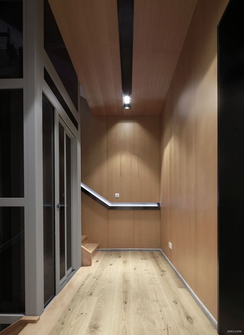 在这样一个高品质的生活，有着多层的空间怎么能少了电梯井的使用。走廊左侧是透明电梯井，转角处是楼梯，整个楼梯采用木饰面全包，墙面简约线条的扶手凹槽暗藏灯带，搭配浅色木质地板，大片木质元素的应用让整个空间有着温馨的色彩。
