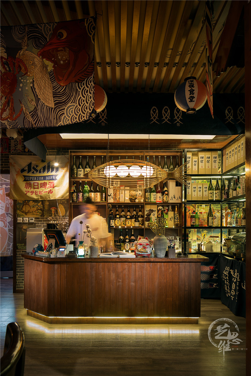 收银台后的酒架摆满了各式日本酒，即解决了收纳，又装饰了空间。天花板的木质装饰与整个空间的风格材质和谐统一。