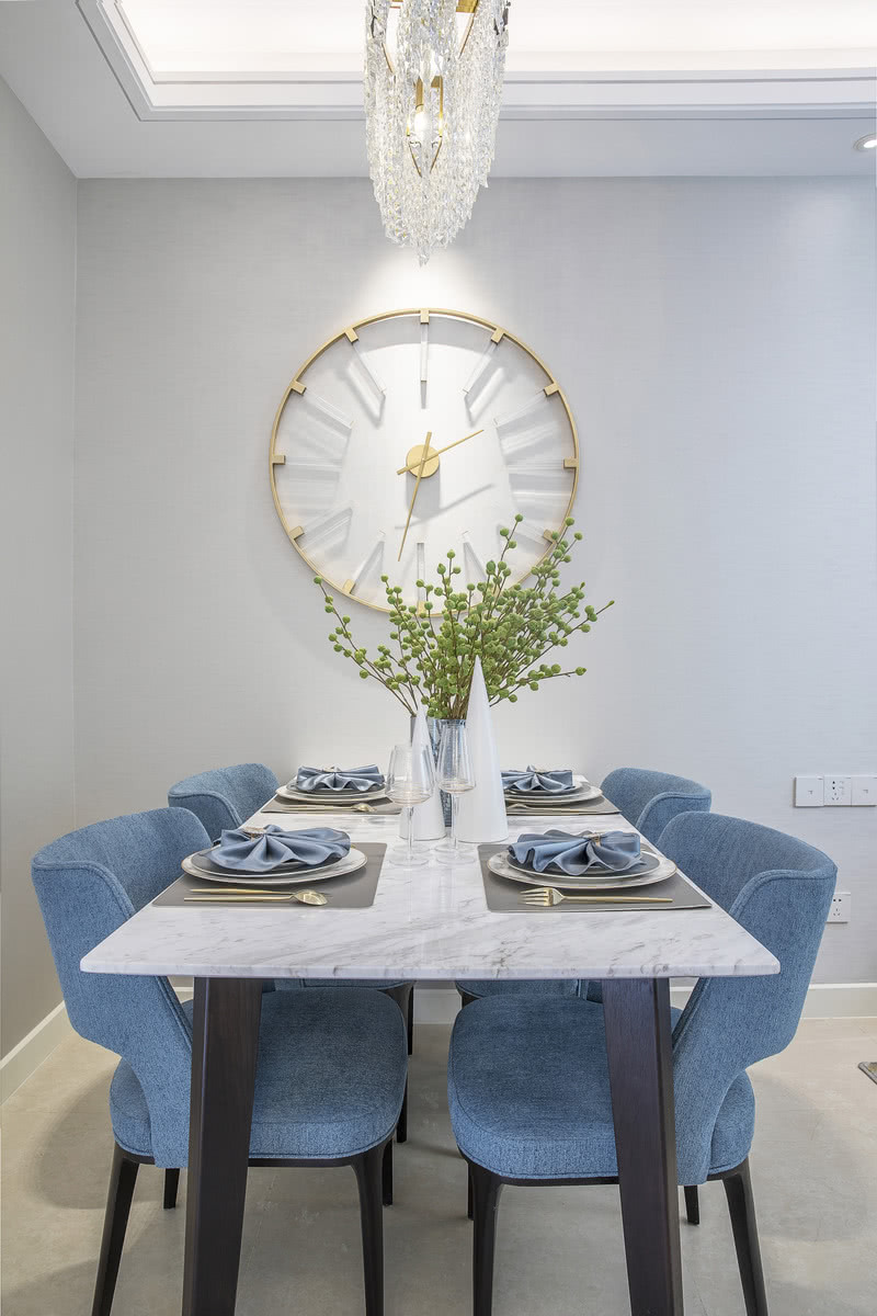 进入餐厅区，映入眼帘的是镂空的墙面简约的时钟，黄钛金的边框、透明亚克力的时间表，既是一个空间记录者又是一个精致的艺术品。蓝色的布艺椅子搭配绿色的植物顿时整个空间显得时尚而又活跃。 