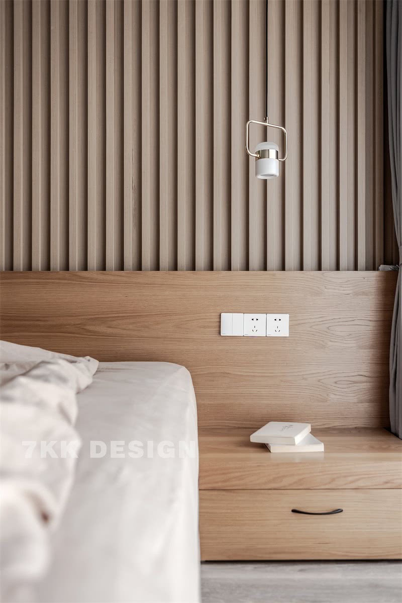 床头背景墙采用实木线条、木纹饰面板搭配落地式木纹饰面板抽屉，自然清新、大方美观。床头柜上方简约吊灯垂下，营造温馨的阅读一角。
