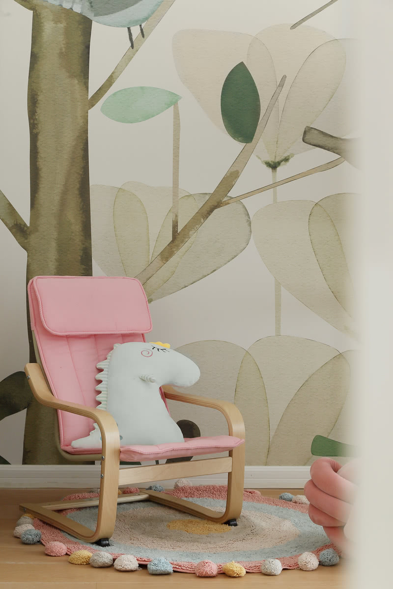 客户说：粉色是女儿最爱的颜色，考虑到粉色上墙会很难把握，于是在选择单品时加以点缀。粉色的摇摇椅上摆着她从小玩的可爱恐龙抱枕，我真想坐着摇啊摇，一秒穿越回童真岁月。背景墙选择了大树小鸟的卡通图案，营造森林的感觉。