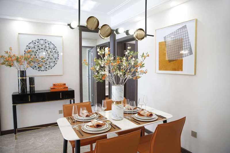    餐厅的在整体色调和材质选择上，与客厅相互呼应，橙色的皮革材质椅子、大理石餐桌以及黑金色吊灯，共同组成餐厅的主要场景。