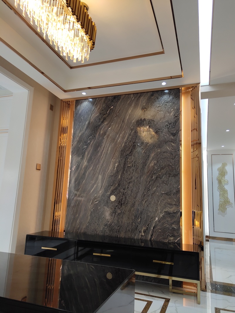 电视背景墙运用整板天然大理石结合原创设计的不锈钢灯带造型。