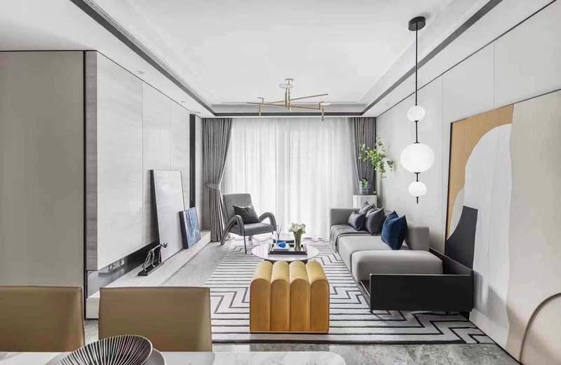  95户型以黄蓝色为主要跳色，首先来到作为主要公共空间的客厅区域。客厅的打造“心意”十足，珊瑚红沙发在经典优雅的廓形中注入了跳跃的色彩，仿佛诉说着空间独一无二的个性。茶几、单人沙发、地毯等单品以黑白灰色诠释，不仅衬托出沙发的大面积跳色，完美地将空间的优雅气质烘托而出。