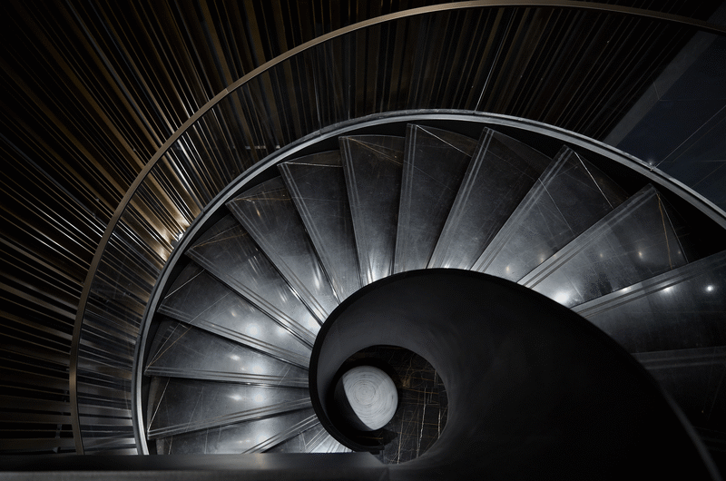 楼梯间部分隐喻亘古不变的太阳系的运行规律，楼梯旋转的曲线如同哥白尼计算出的椭圆轨道，大大小小的石材球体仿佛行星散落，被映射在黑色镜面的墙上，与蓝色的“地球”，构成一副《天体运行论》。