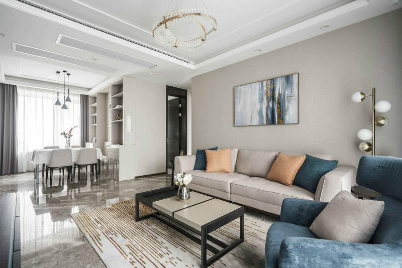 现代简约的灰色布艺主沙发上蓝色+橙色的抱枕，点缀蓝色单椅、非具象纹路地毯的融合地面与家具的过渡，让纯粹的空间，有着恰到好处的温度，灰色与亮色是整个客厅空间的兼容色，灰与橙的搭配，融入蓝色点缀，使简洁沉稳的空间揉入了家的温馨和惬意。从浅色的优雅到深色的沉稳，也是延续经典、引领时尚潮流的绝妙搭配。