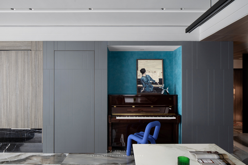电视柜的右边是通入主卧的隐藏门，内嵌式钢琴区域。

艺术涂料的墙面，搭配一把来自法国的Moustache Bold Chair 克莱因蓝的靠背椅，为空间带来了灵动感。
