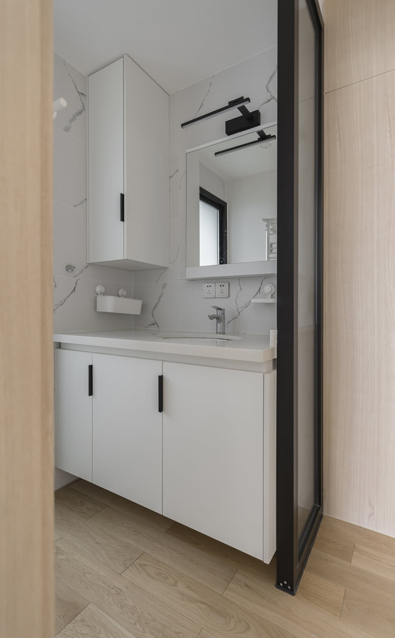 卫生间将洗手台外置，提高了日常使用效率。黑白色调的浴室柜与大理石墙砖的纹理相呼应，视觉上营造了延伸的效果。
