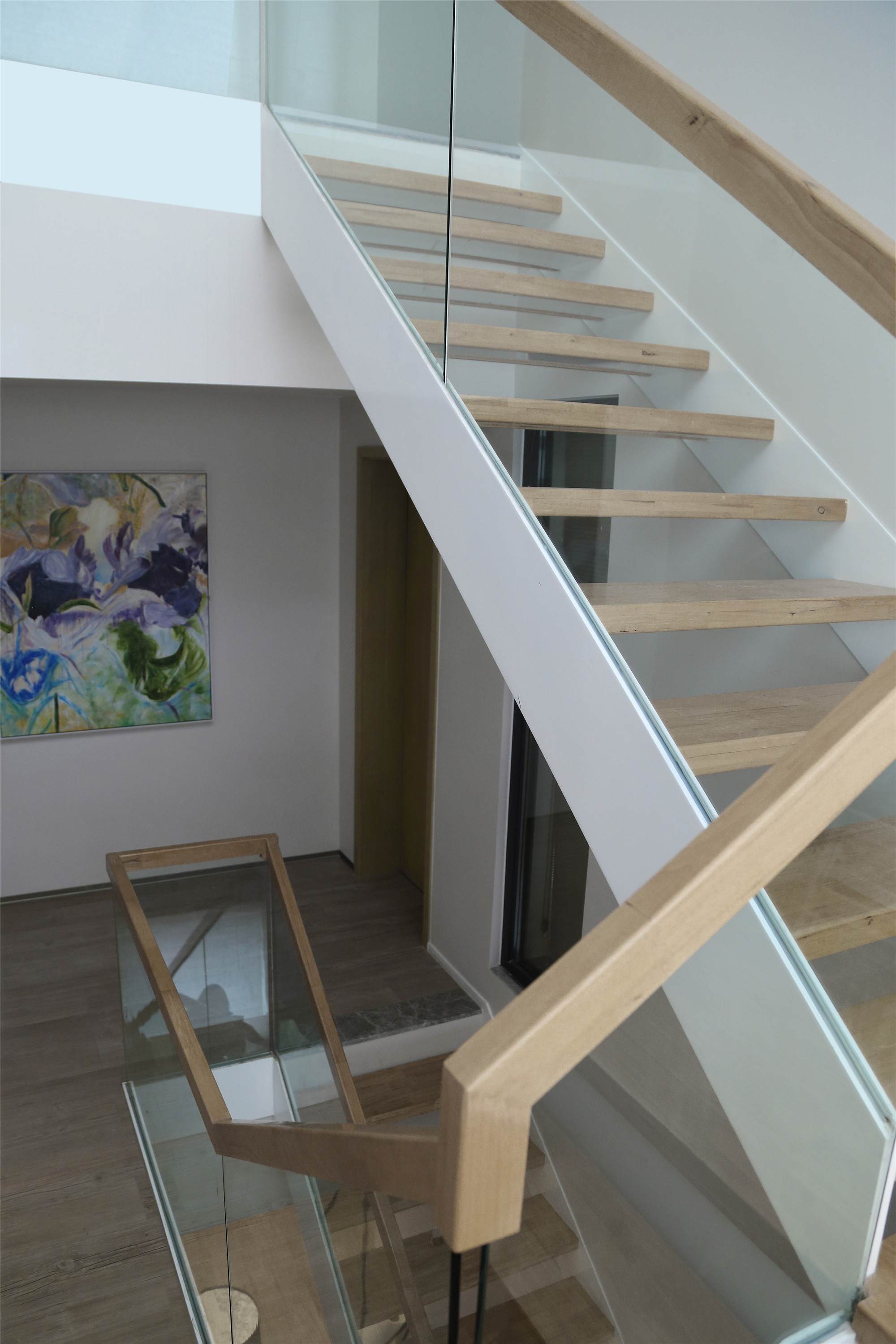 
楼梯玻璃护栏搭配简易的木质镂空台阶，突显了房屋整体的现代风格，十分协调融洽。楼梯结构不仅节省了使用空间，在视觉上也显得轻巧便利，视野无阻，且丰富了空间层次感。
