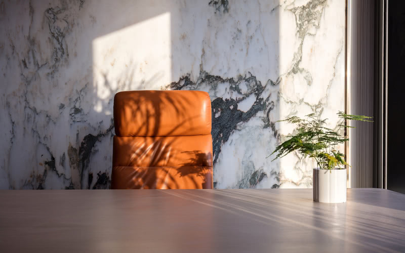 【总经理室1局部图】：山水大理石背景及橘色办公椅在夕阳下的照耀下，显得格外迷人。可于繁忙后欣赏窗外风光、待客会友，也是趣事。即使在现代繁琐的工作与快节奏的生活中，也能得到一处自己心里所属的宁静、淡雅、休闲的惬意。
