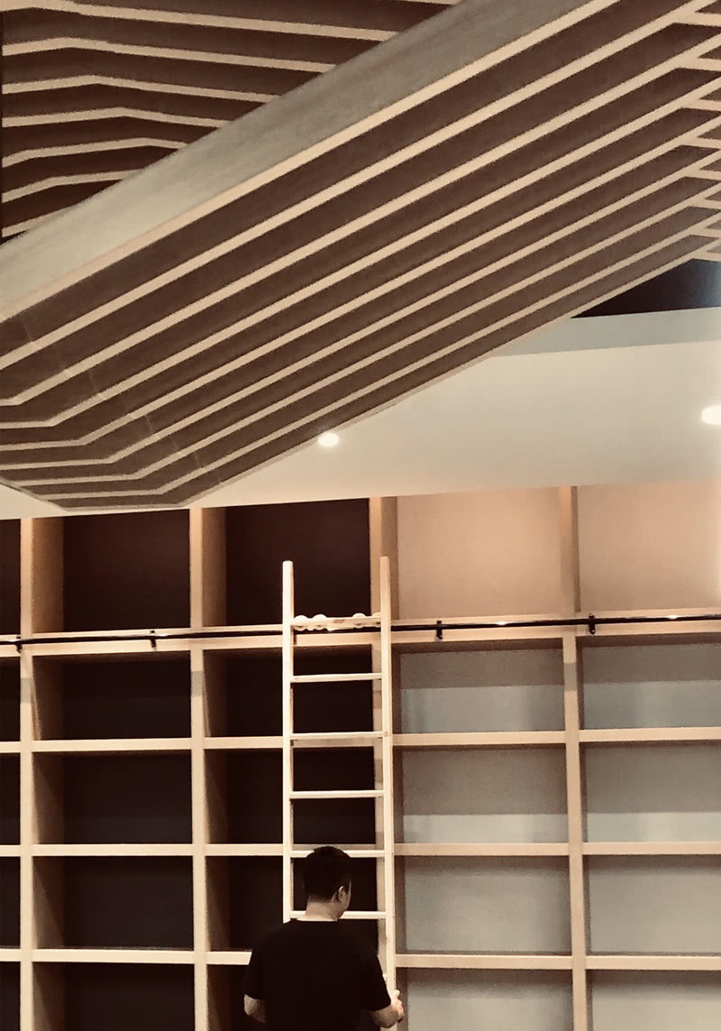 【员工办公区书柜局部图】：大面积的书架在暖光下更能突出书柜的原木材质。