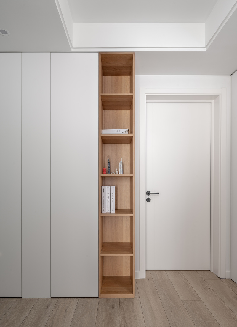 ▲主卧。卧室一侧做白色与木色结合的柜子，部分开放式收纳设计，为单调的空间增添了一丝视觉上的丰富感。