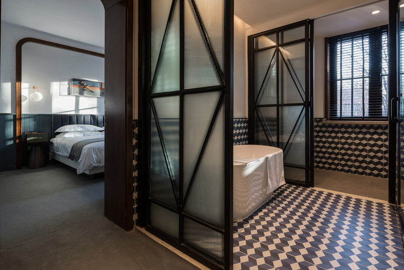 卫浴空间蓝白相间的艺术瓷砖铺陈出立体的几何美学，辅以黑色复古的不锈钢玻璃门，微妙地平衡着整个空间的调性，延续着酒店的整体风格。
