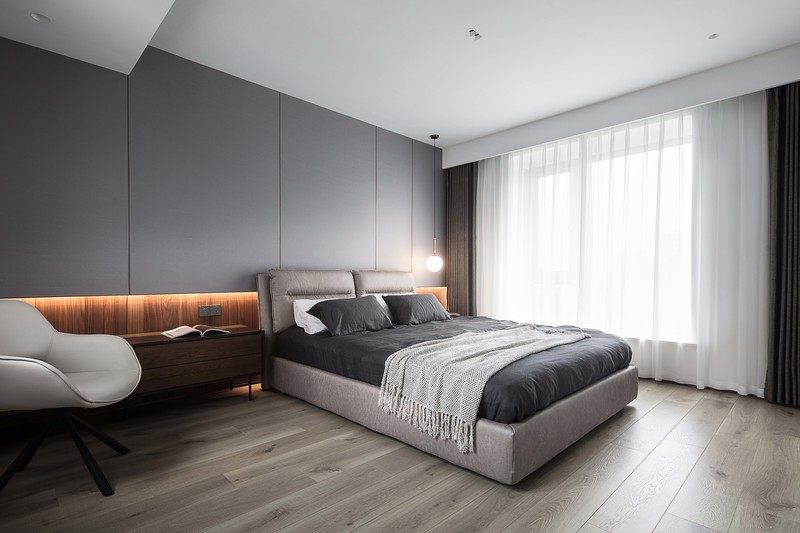主卧以中性的高级灰为主调，床头背景墙用真丝壁布和胡桃木进行拼接，具有变化节奏的线条丰富空间层次。创意床头灯、舒适床品为主人提供一个安心休憩的起居空间。
