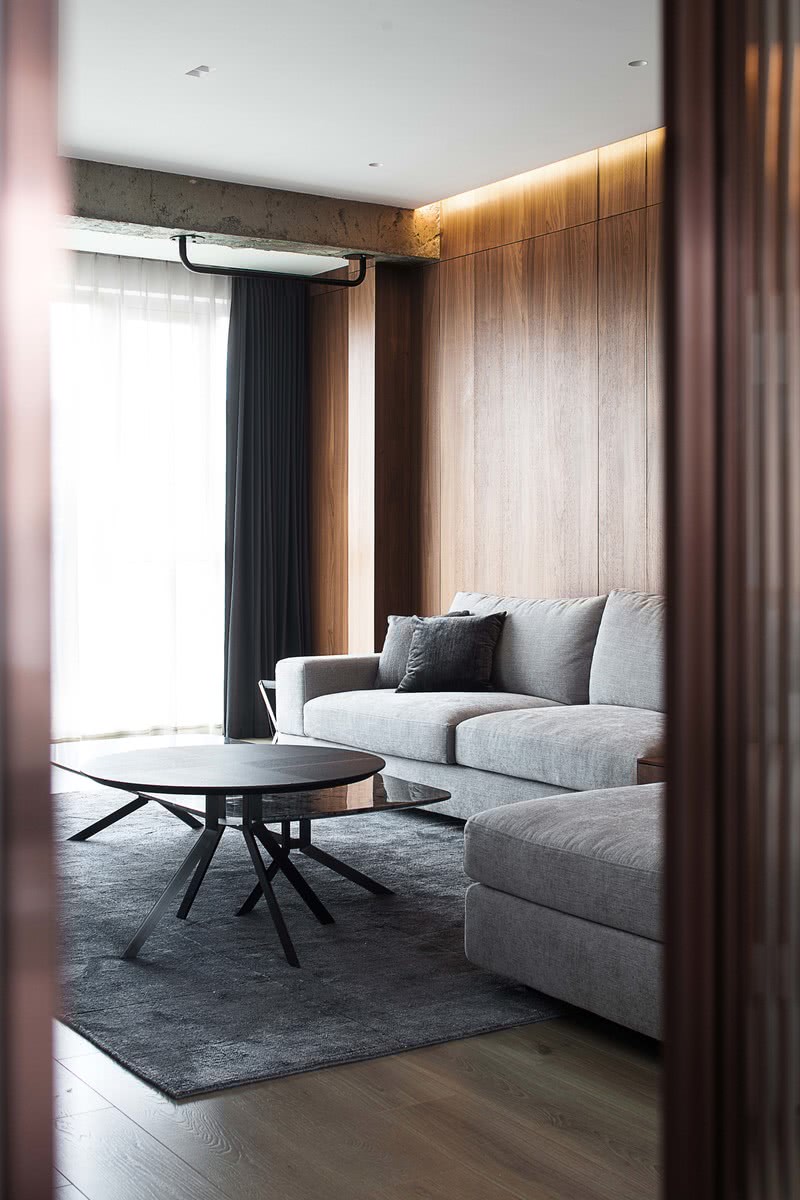 客厅大面积温润低调的胡桃木，为简约的现代家注入无限温柔。柔软的布艺沙发、皮质扶手椅、岩板茶几，材质的融合碰撞，营造空间的秩序感和节奏感。