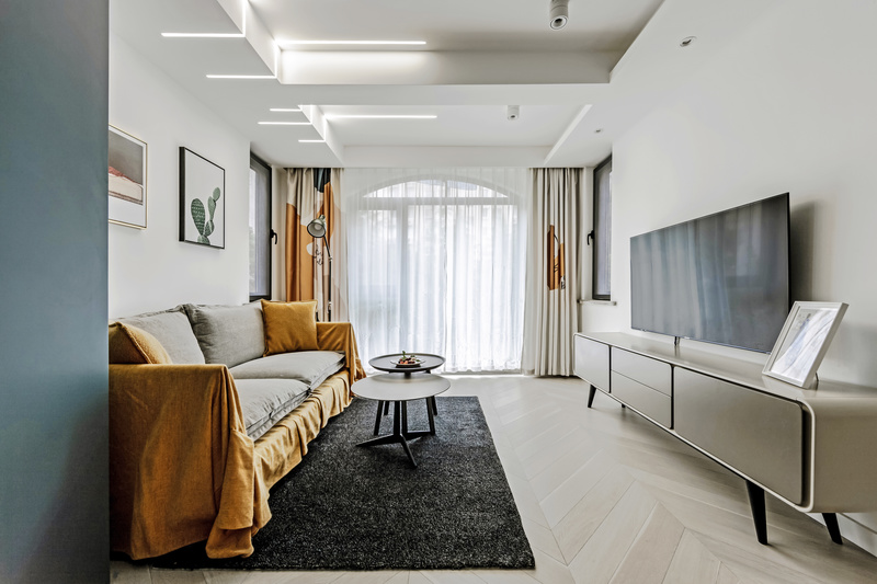 深灰色的地毯，浅灰色的沙发，白色的墙面，不同深浅色调的搭配让空间层次分明。暖黄色的加入能让原本冷酷的空间转换成为一个带有暖意、温馨的客厅。