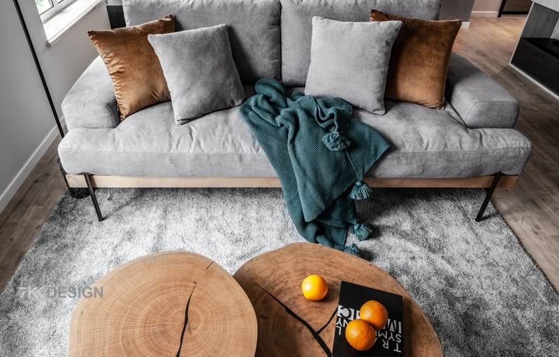 北欧风情的棉质沙发，是业主精心挑选出来的，沙发灰度也是刚刚好，不深不浅的水泥色，搭配着客厅整体的灰色主色调，再配上橙色的抱枕，蓝色的毛毯，木系的茶几，冷暖结合，很是舒适。