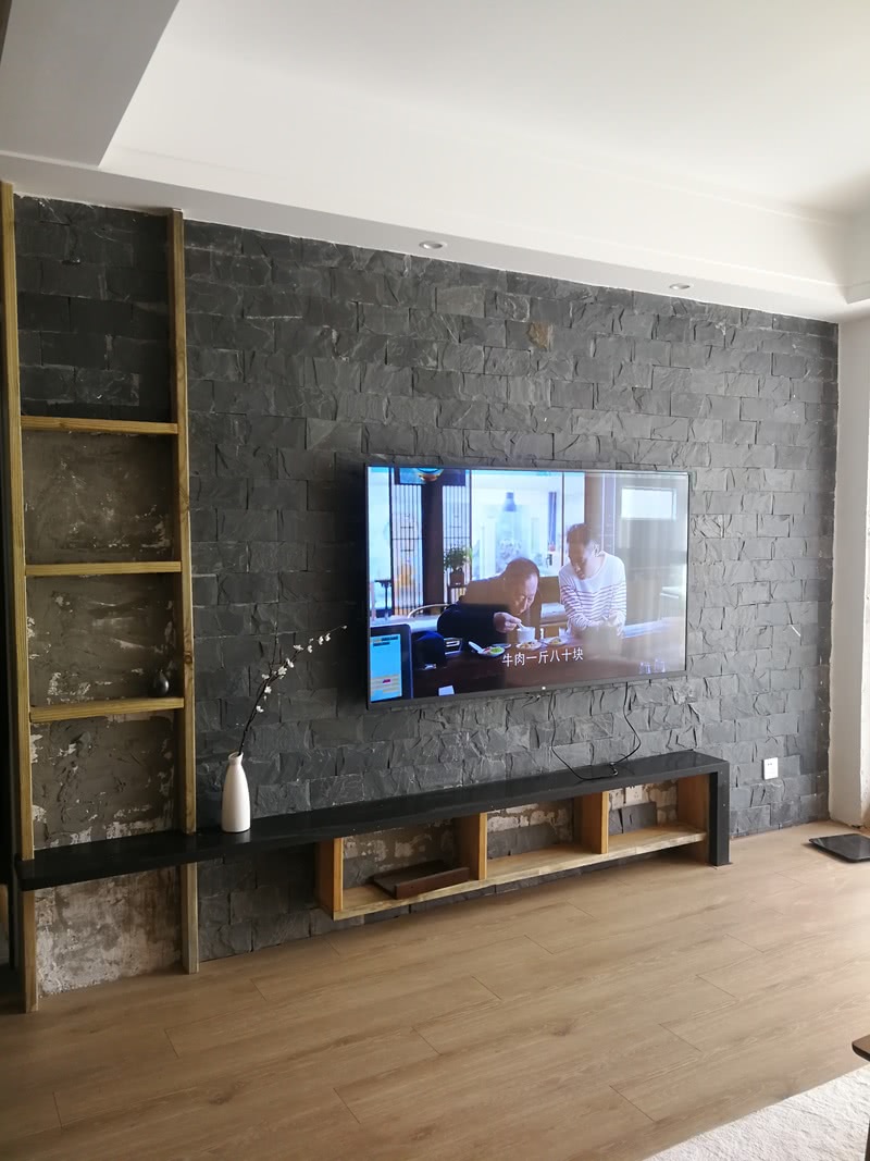 电视背景墙有粗糙石材饰面，左边防腐木展架