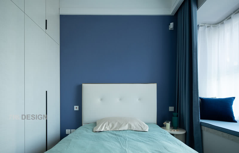 次卧现在主要是女方的母亲居住，后期等小孩长大可以作为女儿房。父母在别的地方有居住的空间。为了空出衣柜的空间，床的尺寸选择了1450mm2000mm，整体空间选择不同深浅的蓝色系搭配静谧的睡眠空间。靠墙一层定制到顶的衣柜作为次卧的收纳空间使用。
