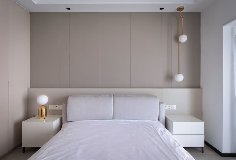 卧室延续了整体空间纯净的色调 ，空间布置以暖灰色硬包饰面拼接出若隐若现的线条，搭配金属吊灯，为空间增添了细腻的灵动感。