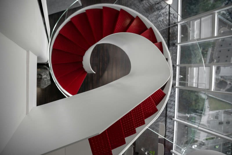 主厅正中的旋转步梯连接着一二层，白色曲面、螺旋弧线、通透护墙、红色阶梯，让人仿佛沉浸在未来光影旋律里，又好似穿梭在时间漫游旋涡中。