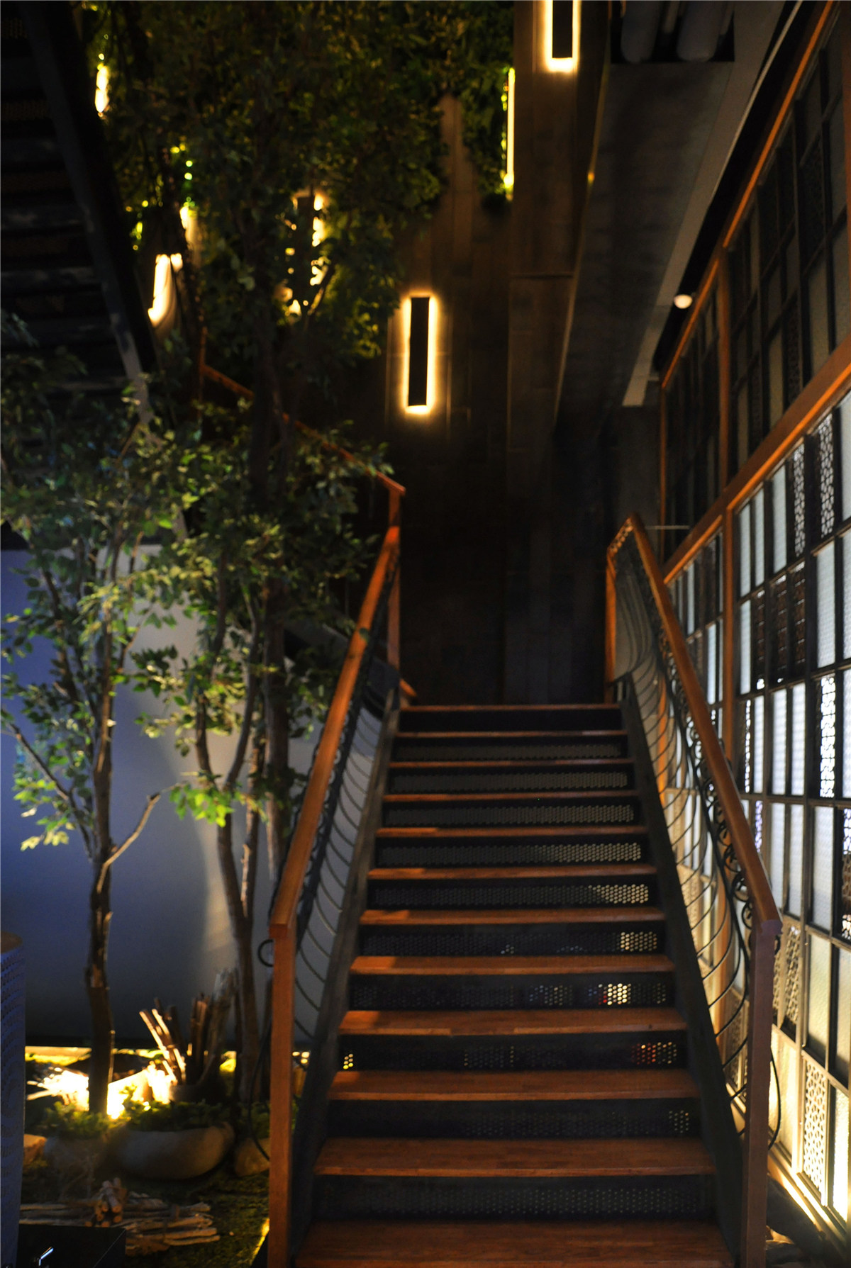 镂空造型的铁板、原木踏步、异域风情的精致扶手，各式风格混搭的楼梯很有看点。拾级而上，满眼木色的温馨和绿植的清新。各种样式的花玻璃、精心布置的中空小景以及恰到好处的灯光效果，将餐厅独特的空间气质延伸至二楼。